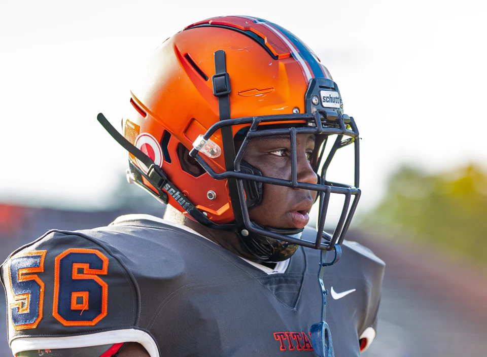 Titans football player wearing an orange helmet and gray jersey on the field